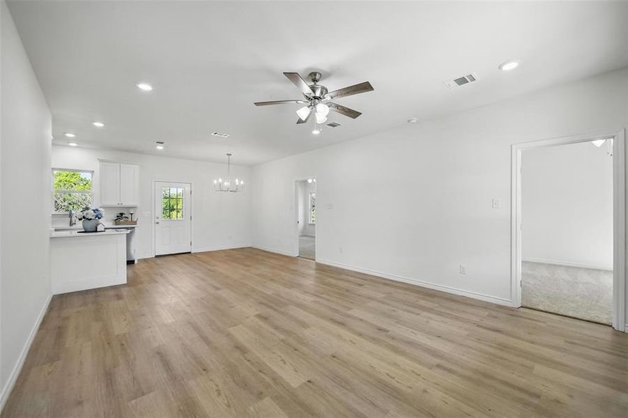 Unfurnished living room with ceiling fan, a chandelier, light wood-style floors, recessed lighting, and baseboards Unfurnished living room with ceiling fan, a chandelier, light wood-style floors, recessed lighting, and baseboards