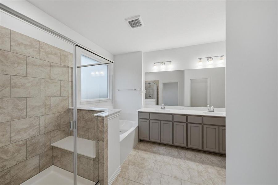 Bathroom with a shower stall, double vanity, and a garden tub