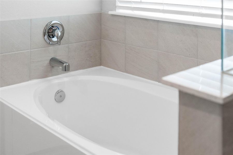 Unwind after a long day in the deep, corner soaking tub, a perfect sanctuary for relaxation. The tub is accented by stylish, warm-toned fixtures.