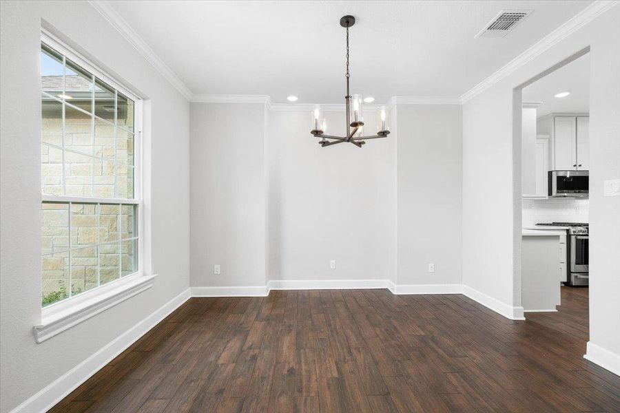 Unfurnished dining area with a chandelier, healthy amount of natural light, crown molding, dark wood-style flooring, and recessed lighting Unfurnished dining area with a chandelier, healthy amount of natural light, crown molding, dark wood-style flooring, and recessed lighting