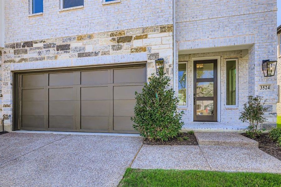 Entrance to property featuring stone siding, brick siding, and driveway