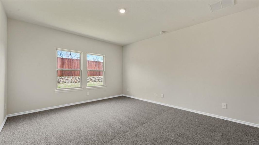 Spacious room featuring neutral carpeting, light-toned walls, and two windows with white trim