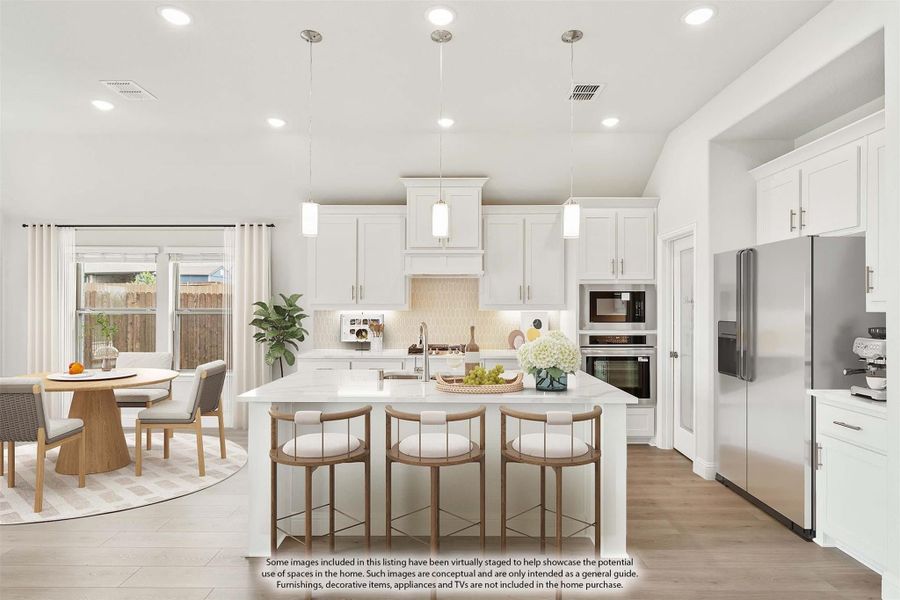Open kitchen with white cabinets, large island with bar seating, stainless appliances, and adjacent dining area with hardwood floors Open kitchen with white cabinets, large island with bar seating, stainless appliances, and adjacent dining area with hardwood floors