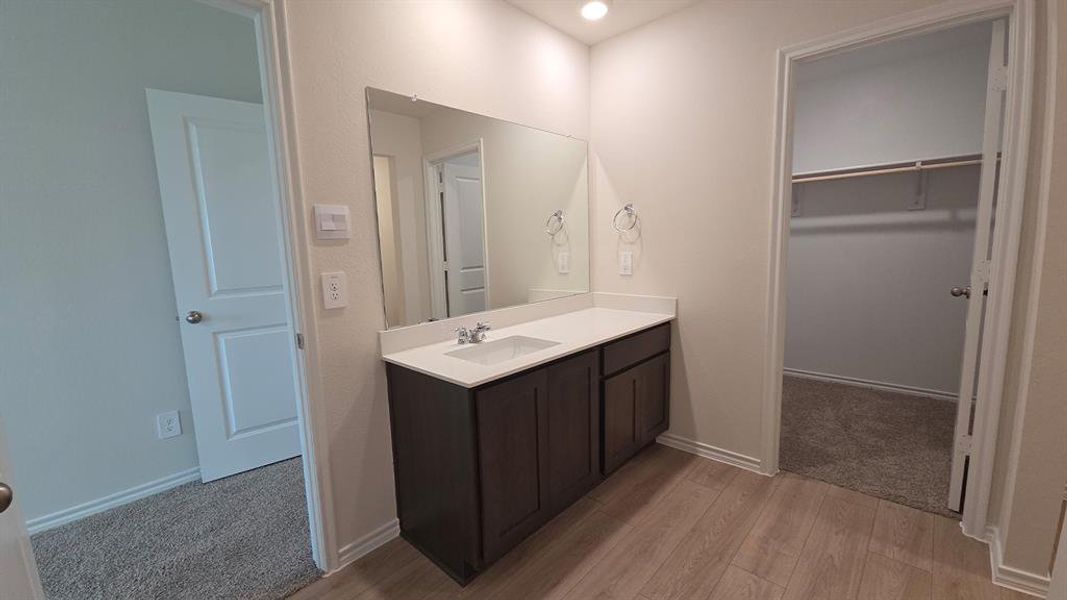 Vanity area featuring a single basin with a white countertop, dark wood-finish cabinetry, and an integrated mirror Vanity area featuring a single basin with a white countertop, dark wood-finish cabinetry, and an integrated mirror