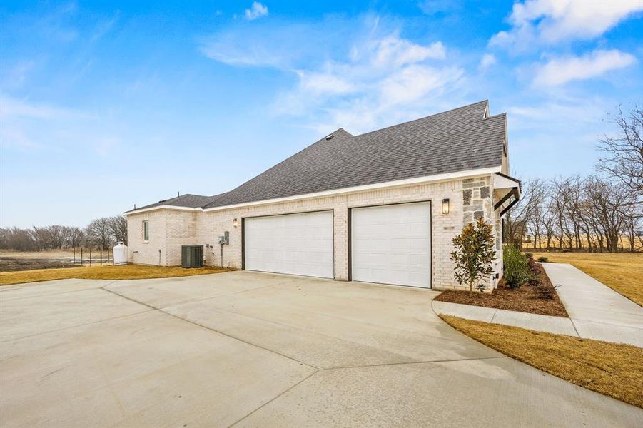 View of side of property featuring a shingled roof, brick siding, concrete driveway, and a garage View of side of property featuring a shingled roof, brick siding, concrete driveway, and a garage