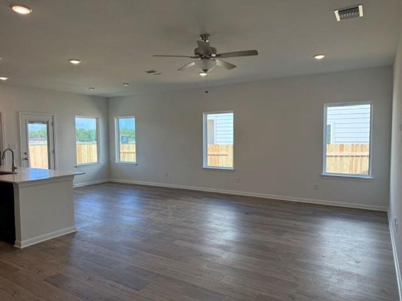 Open-concept living area featuring wood-finish flooring, recessed lighting, and a ceiling fan Open-concept living area featuring wood-finish flooring, recessed lighting, and a ceiling fan