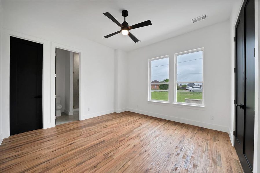 This room features wood-look flooring, white walls, and a ceiling fan with integrated lighting