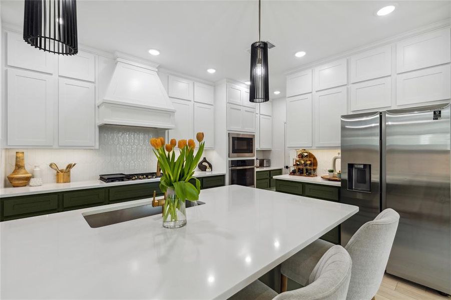 Kitchen featuring light countertops, tasteful backsplash, a breakfast bar, appliances with stainless steel finishes, and premium range hood Kitchen featuring light countertops, tasteful backsplash, a breakfast bar, appliances with stainless steel finishes, and premium range hood
