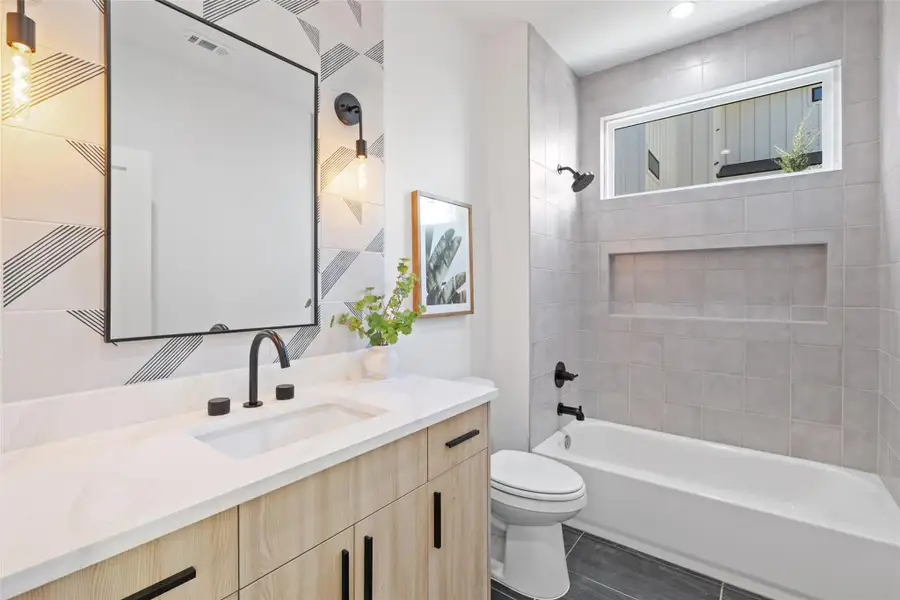 Full bathroom featuring tiled shower / bath combo, vanity, toilet, and tile patterned flooring