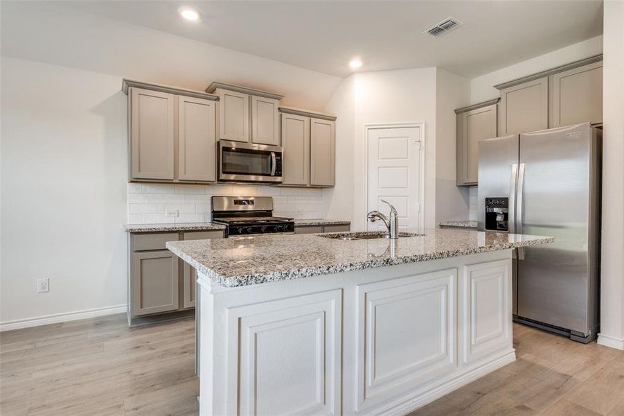 Kitchen with decorative backsplash, appliances with stainless steel finishes, light stone countertops, gray cabinets, and recessed lighting