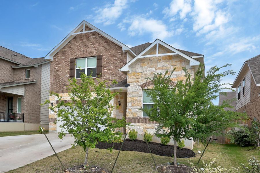 Two-story residence featuring a brick and stone facade, gabled rooflines, and a covered entry
