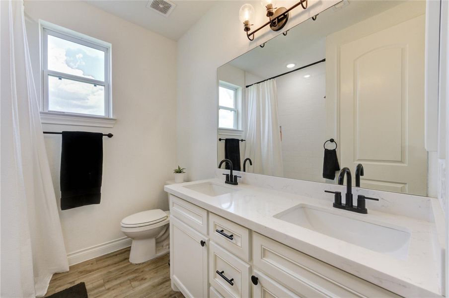 Elegant bathroom featuring dual sinks, quartz countertops, and stylish black fixtures