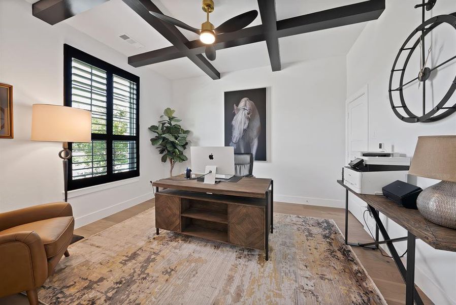 Room featuring light wood-finish flooring, white walls, and a white ceiling with dark exposed beams Room featuring light wood-finish flooring, white walls, and a white ceiling with dark exposed beams
