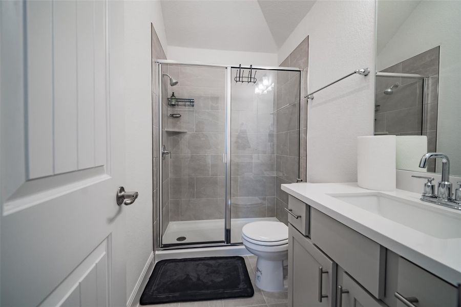 A well-appointed bath features a tiled walk-in shower and a modern vanity with ample counter space.