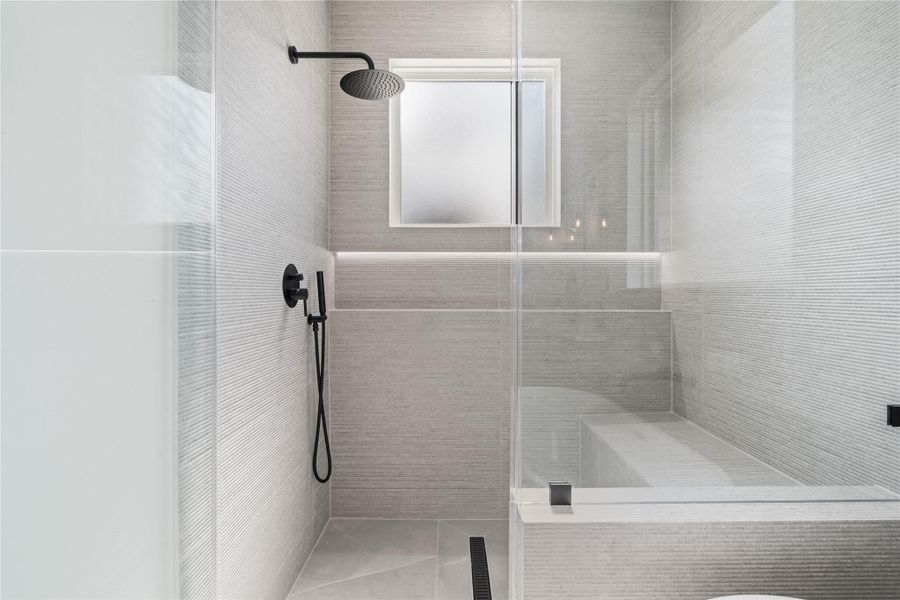 Walk in shower complete with a built-in bench and an oversized shampoo niche illuminated by LED lighting, wrapped in a luxurious fluted tile, adding a modern touch.