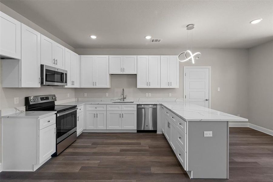 Kitchen featuring white cabinetry, dark hardwood / wood-style flooring, light stone counters, stainless steel appliances, and hanging light fixtures