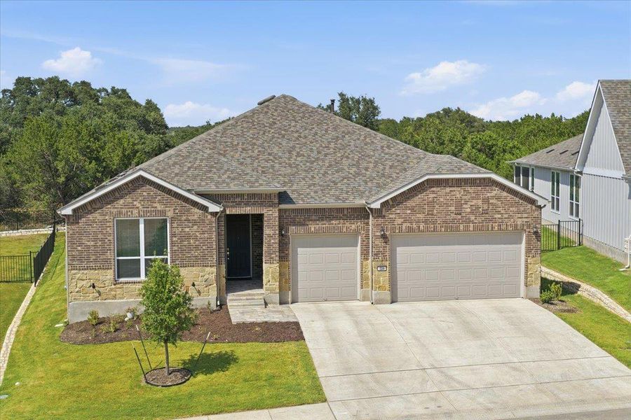 A well-maintained facade with brick and stone accents, featuring an attached two-car garage and a gently sloped lawn. A well-maintained facade with brick and stone accents, featuring an attached two-car garage and a gently sloped lawn.