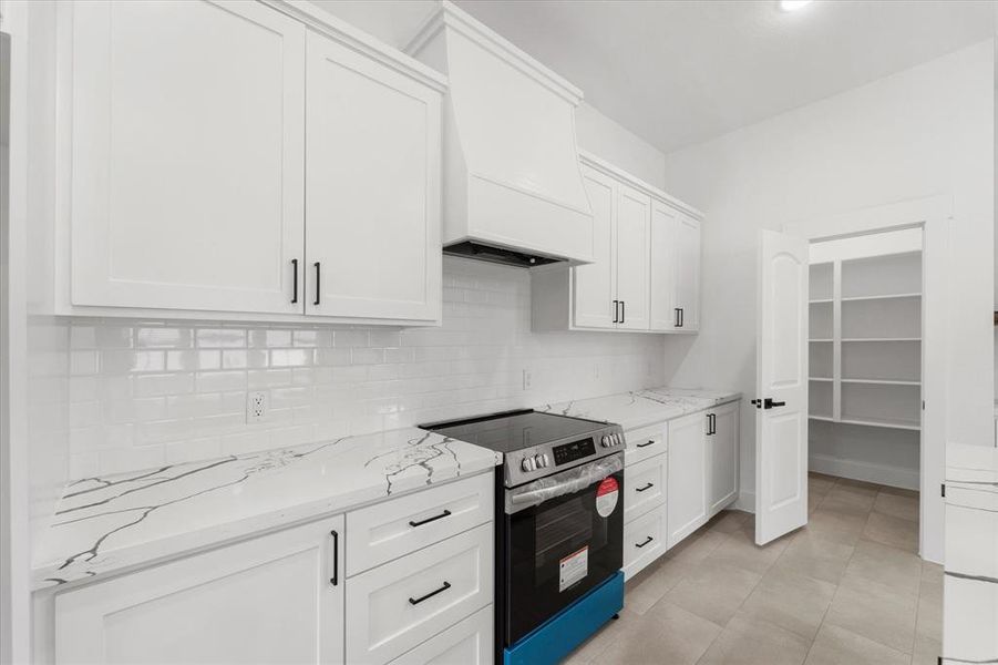 Your kitchen is a chef’s dream, featuring stainless steel appliances, custom cabinetry with a beautifully crafted hood vent, and elegant quartz countertops complemented by a classic subway tile backsplash. Don’t forget about the walk-in pantry pictured to the right!