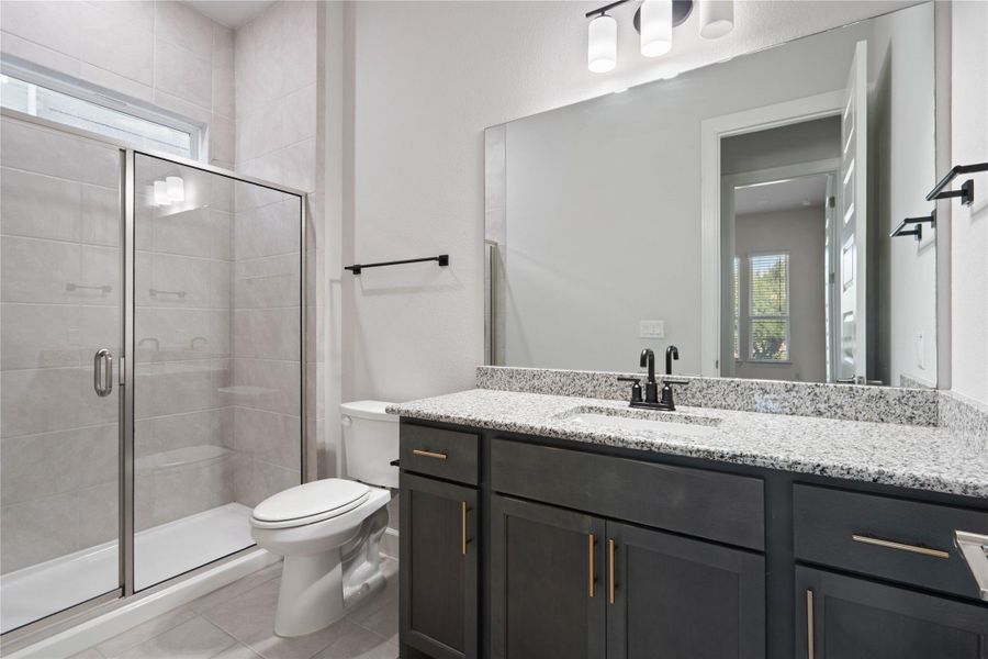 Polished granite counters and a glass-enclosed shower create a modern aesthetic in this bathroom.
