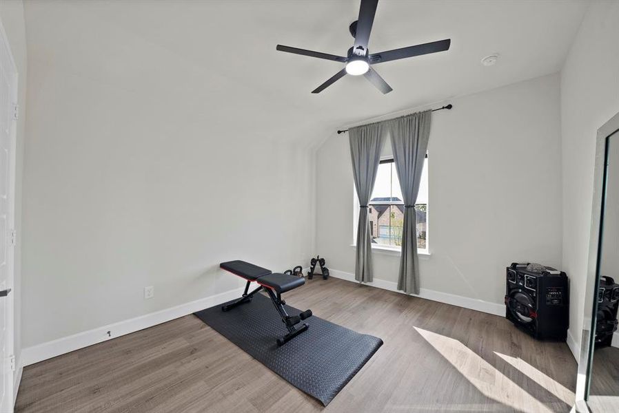 Versatile room featuring wood-finish flooring, a window with gray drapes, and a ceiling fan with integrated lighting Versatile room featuring wood-finish flooring, a window with gray drapes, and a ceiling fan with integrated lighting