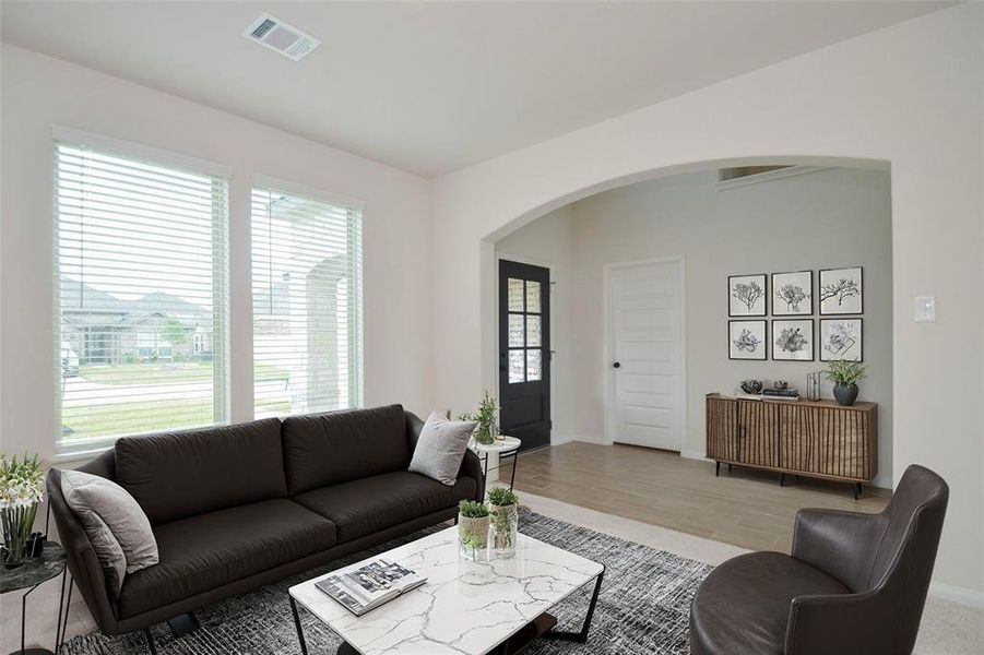 The formal living area features large windows that flood the room with sunlight. Soft carpeting creates a warm, inviting space perfect for intimate gatherings or quiet relaxation. The arched entryways offer seamless flow to other areas of the home, enhancing its open and airy design.