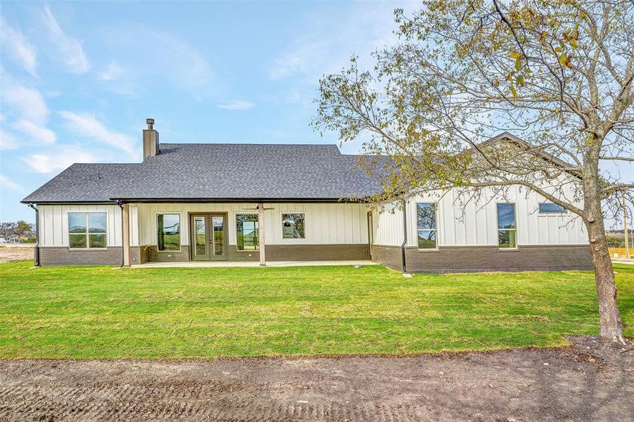 Rear view of house featuring french doors and a lawn