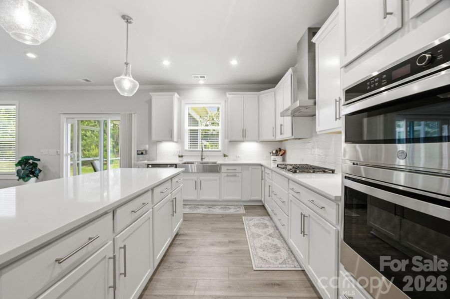 Kitchen from Butlers Pantry. Quartz counter tops stainless steel appliances, gas range with hood.
