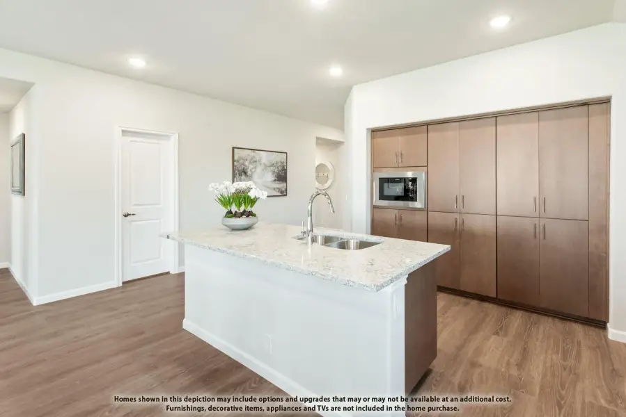 Kitchen with white island, granite countertop, built-in microwave, and tall brown wood cabinets on hardwood floors