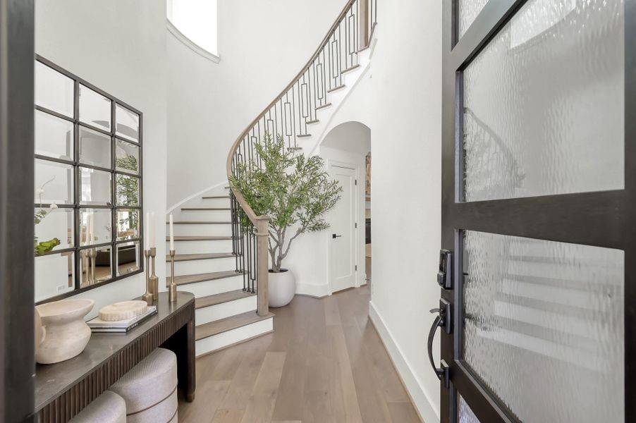 Step into a grand entryway with soaring ceilings that immediately set the tone for the home’s elegant design. A sweeping curved staircase creates a striking architectural focal point upon arrival.