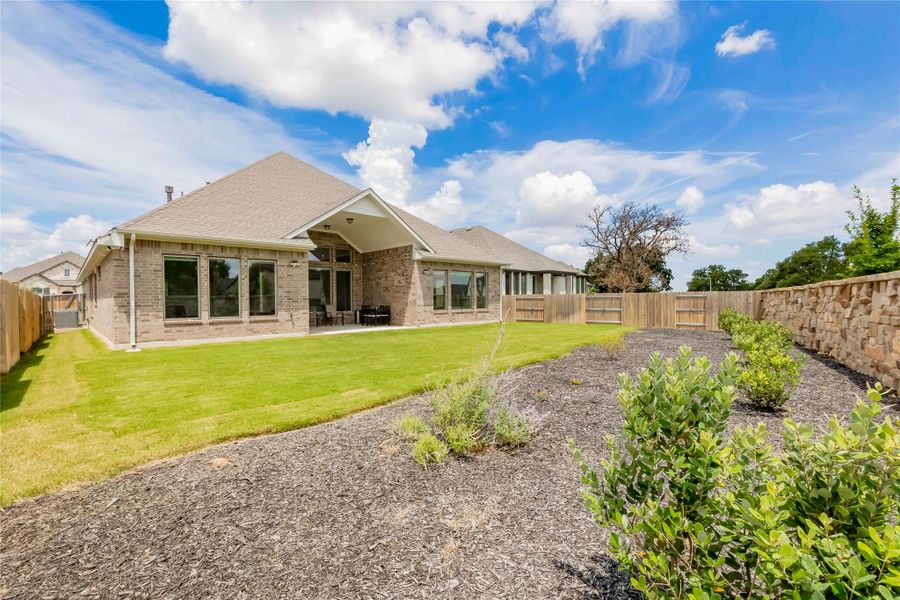 A well-maintained lawn and planted garden beds enhance this inviting outdoor living space.