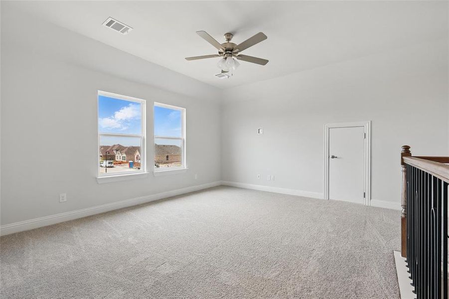 Carpeted empty room featuring baseboards, visible vents, and a ceiling fan