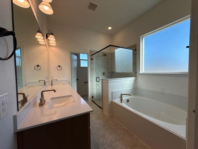 Bathroom with double vanity, a bath, a stall shower, a chandelier, and light tile patterned floors