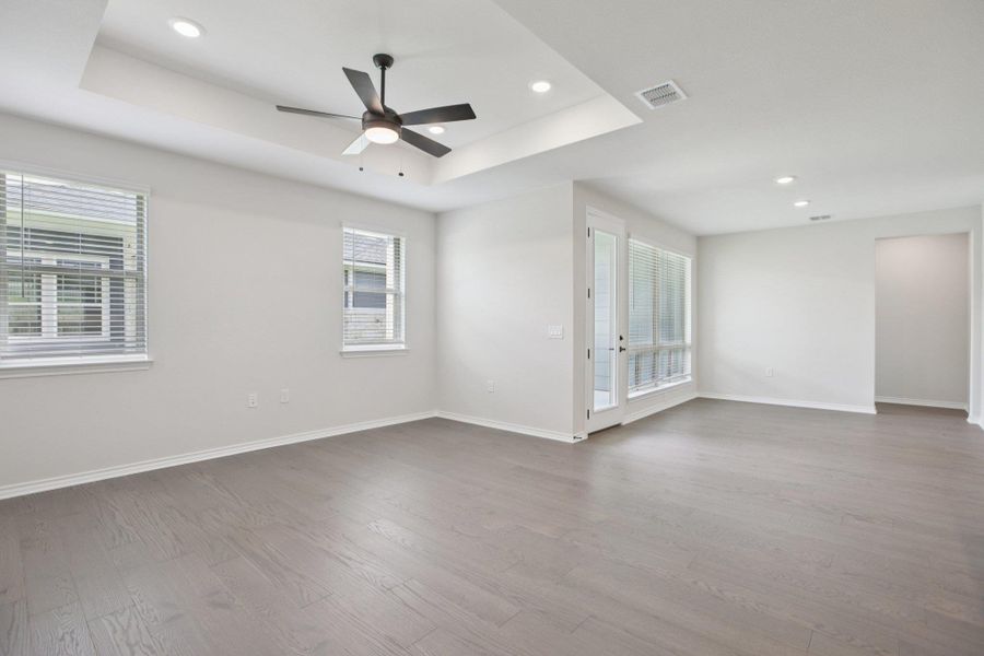 Empty room featuring a raised ceiling, light wood finished floors, plenty of natural light, and recessed lighting