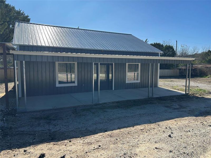 Rear view of property with board and batten siding and a metal roof Rear view of property with board and batten siding and a metal roof