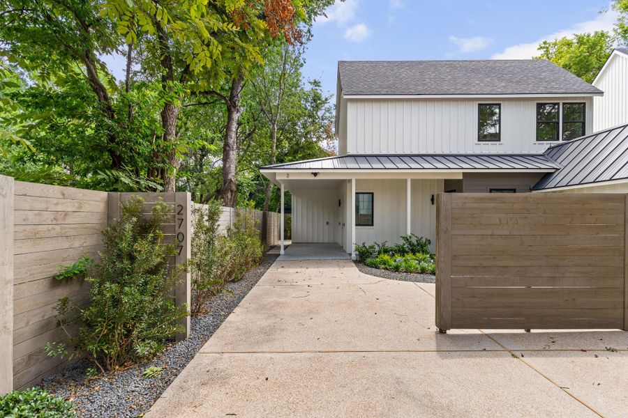 View of front of house featuring a carport, a gate, driveway, a metal roof, and board and batten siding View of front of house featuring a carport, a gate, driveway, a metal roof, and board and batten siding