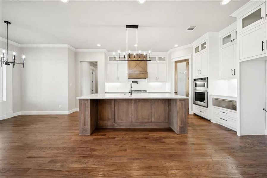 Kitchen with a kitchen island with sink, a notable chandelier, and decorative light fixtures