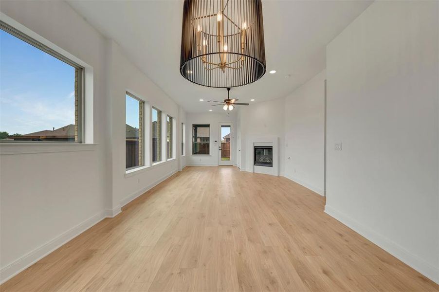 Spacious interior featuring light wood-finish flooring, a contemporary chandelier, multiple windows for ample light, a modern fireplace, and recessed ceiling lights