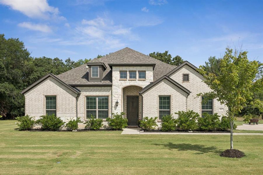 Traditional home featuring stone and brick siding and well maintained front yard.
