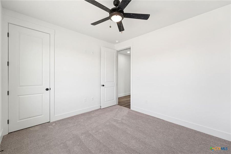 A well-lit bedroom features plush carpeting and a modern ceiling fan, offering a comfortable personal retreat. A well-lit bedroom features plush carpeting and a modern ceiling fan, offering a comfortable personal retreat.