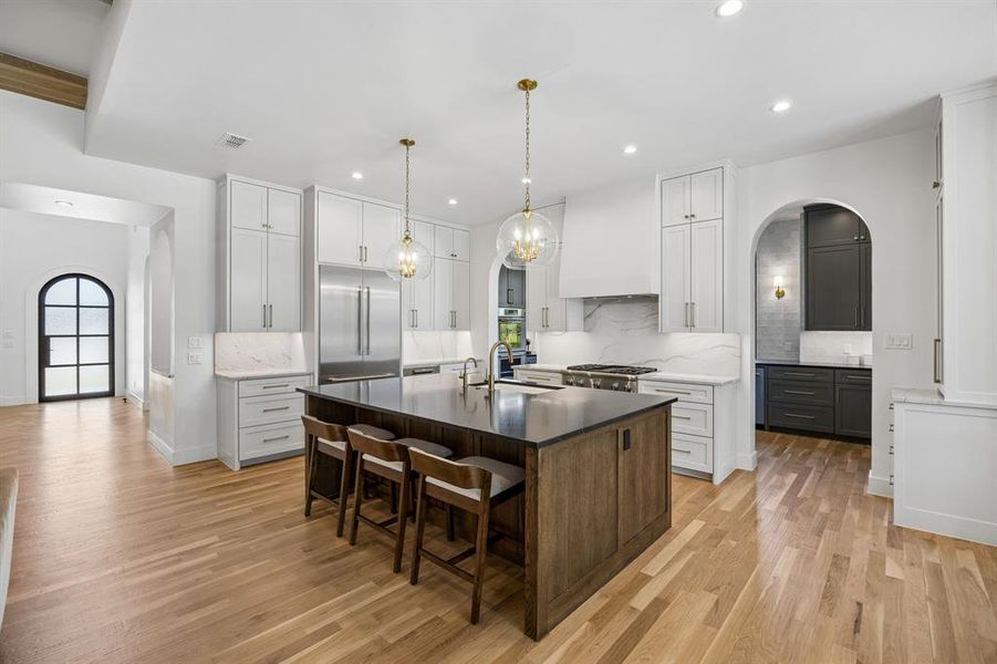 Showcasing elegant floor-to-ceiling cabinetry providing ample storage, the space features charming arched doorways that lead seamlessly to a well-equipped chef's prep pantry.