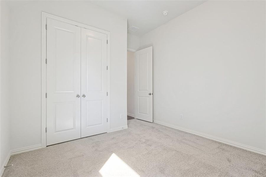 Unfurnished bedroom featuring light carpet and a closet