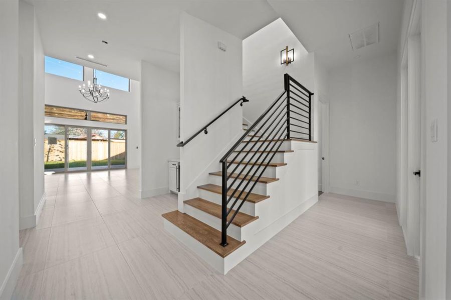 This beautifully designed stairway serves as a centerpiece of the home, featuring sleek black metal railings and warm wood treads for a modern yet inviting look. The open design allows natural light to flow freely, complementing the spacious and airy atmosphere of the living area. Perfectly blending style and functionality, this stairway adds a touch of elegance to the home's contemporary architecture