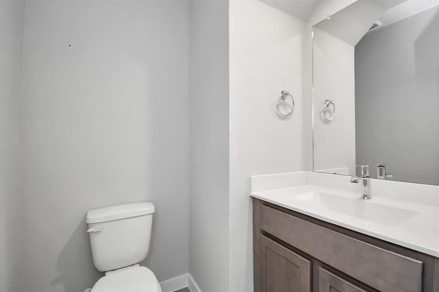 Step into this bright and airy half bath, where a sleek pedestal sink and modern hardware elevate the space with contemporary charm. Photo shown is example of completed home with similar plan.