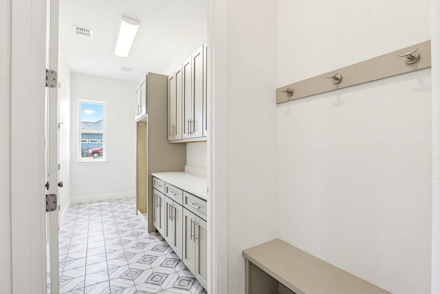 Functional mudroom with stylish geometric tiled flooring, ample storage cabinetry, and convenient coat hooks.