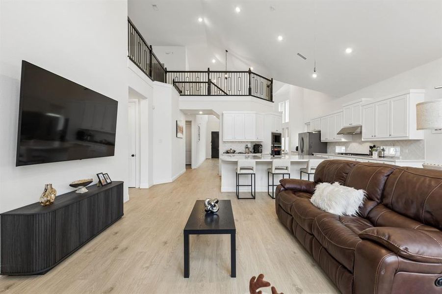 Expansive open-concept living area featuring a vaulted ceiling and wood-finish flooring