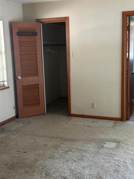 Unfurnished bedroom featuring a walk in closet and light carpet