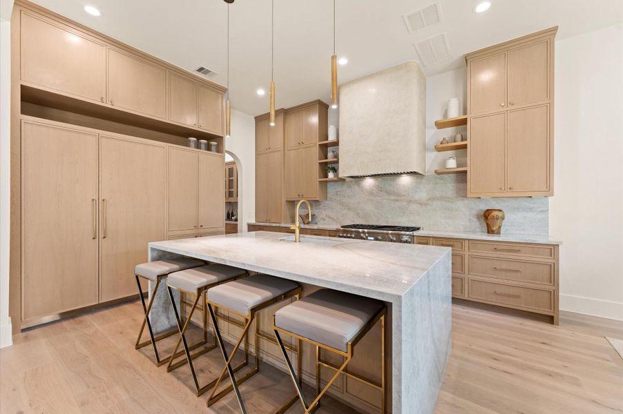 The gourmet kitchen boasts white oak custom inset cabinetry, Taj Mahal quartzite countertops and a striking custom curved plaster range hood. The gourmet kitchen boasts white oak custom inset cabinetry, Taj Mahal quartzite countertops and a striking custom curved plaster range hood.