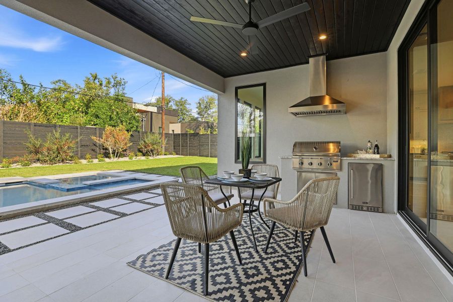 Fenced backyard featuring an outdoor kitchen, a patio, outdoor dining space, and a ceiling fan Fenced backyard featuring an outdoor kitchen, a patio, outdoor dining space, and a ceiling fan