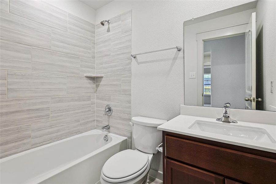 Full bathroom featuring tiled shower / bath, vanity, and toilet