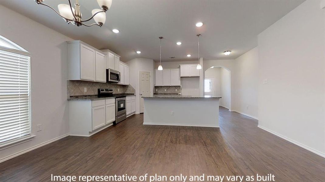 Kitchen with hanging light fixtures, arched walkways, stainless steel appliances, white cabinetry, and a kitchen island with sink Kitchen with hanging light fixtures, arched walkways, stainless steel appliances, white cabinetry, and a kitchen island with sink